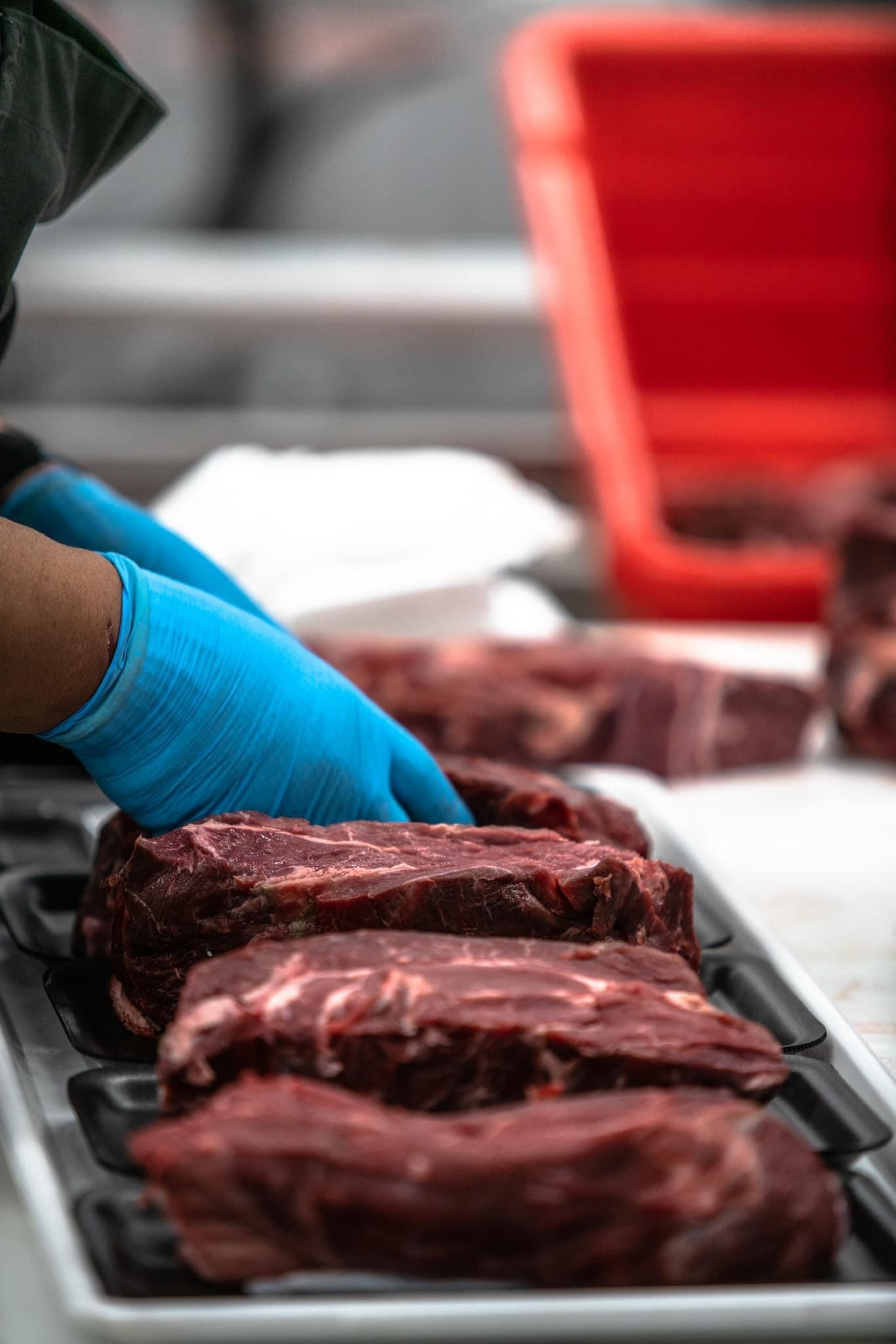 Fresh beef cuts being prepared by hand during processing at a small-scale supplier.