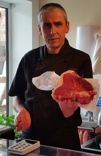 Tony Reynolds holding a steak inside Reynolds Butchers in Lancashire.